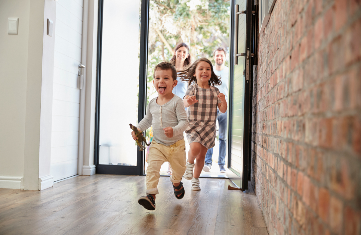 Young family opening the door of their new home and kids running into the hallway