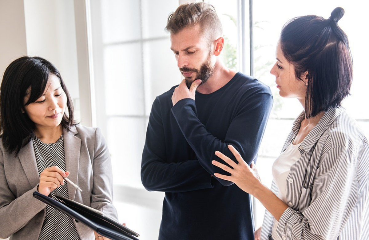 Real estate agent providing a property appraisal to young couple in their home